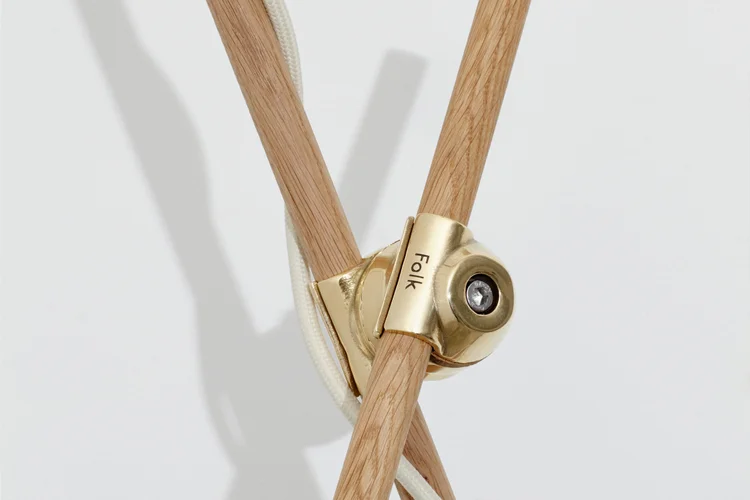 Close-up of a cast brass Folk clamp joining two oak lamp stems.